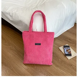 Dettaglio della borsa tote in velluto a coste rosa con etichetta Fashion e trama morbida