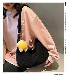 Detail of waffle quilted black shoulder bag with a yellow star plush charm for women