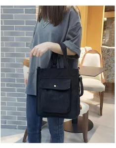 Detailed view of black corduroy shoulder bag with front flap pocket and gold snap button
