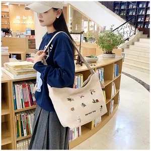 Detail view of beige corduroy tote bag with floral embroidery and Harvest Day text