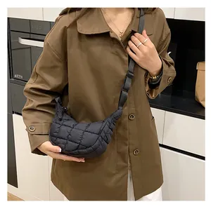 Detail of black quilted puffer crossbody bag with cloud texture and adjustable strap