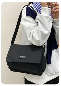 Vista laterale di una borsa a tracolla in tela nera con etichetta fashion e cinghia