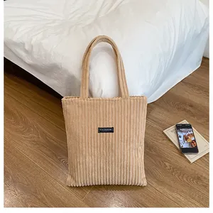 Dettaglio borsa tote in velluto a coste beige con trama rigata ed etichetta nera