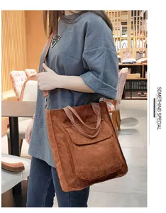 Detail of brown corduroy tote bag featuring a front pocket and wide shoulder strap