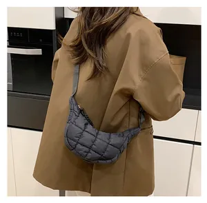 Detail of black quilted dumpling bag on a model wearing a brown blazer