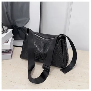 Détail de la texture tressée noire du sac avec bandoulière réglable et zip argenté