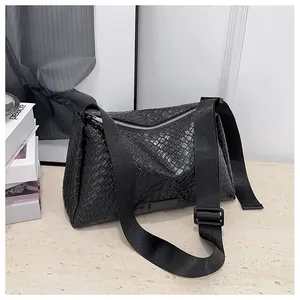 Gros plan sur le cuir tressé noir et la bandoulière en nylon réglable du sac porté épaule