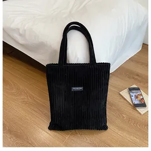 Dettaglio della borsa tote in velluto a coste nero con etichetta Fashion su pavimento