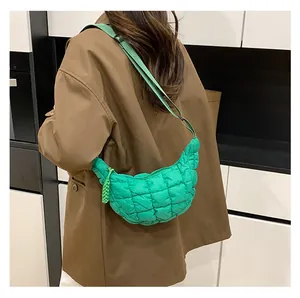 Side view of a bright green quilted crescent crossbody bag worn over a brown jacket