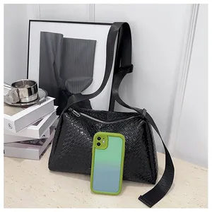 Gros plan du sac bandoulière tressé noir avec un smartphone pour montrer la grande capacité