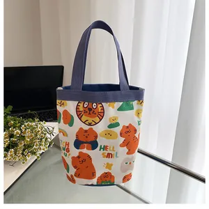 Détail d'un sac seau en toile avec imprimé tigre orange et poignées tissées bleues