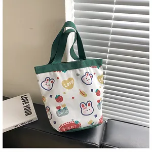 Close-up of white canvas bucket bag with green handles and cute cartoon patterns