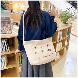 Detail of beige corduroy tote with Harvest Day embroidery in a cozy bookstore setting