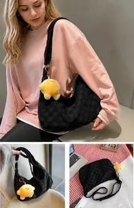 Detail view of black waffle texture hobo bag with a cute yellow chick plush charm