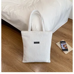 Dettaglio borsa tote in velluto a coste bianco con etichetta Fashion e trama a coste