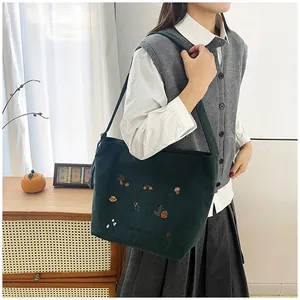 Detail of green corduroy tote bag with Harvest Day autumn embroidery and long strap