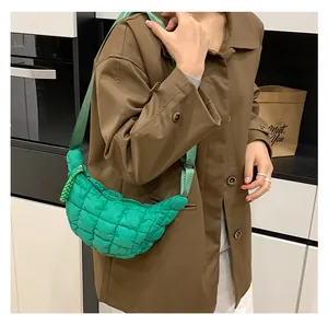 Detail of bright green quilted puffer crossbody bag worn with a casual coat in kitchen