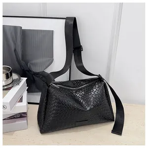 Détail de la texture en cuir tressé noir et du zip argenté sur le sac à bandoulière