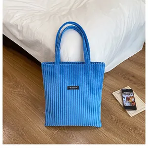 Dettaglio della trama in velluto a coste blu della borsa tote con etichetta Fashion nera