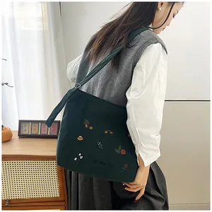 Close-up of dark green corduroy tote bag with floral embroidery and Harvest Day text