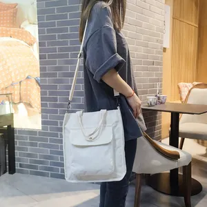 White corduroy tote bag with adjustable shoulder strap shown in a casual indoor setting