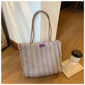 Detail view of plush grey tote bag featuring striped texture and fashion girl logo