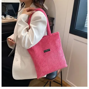 Dettaglio della borsa tote in velluto a coste rosa con etichetta Fashion indossata in ufficio