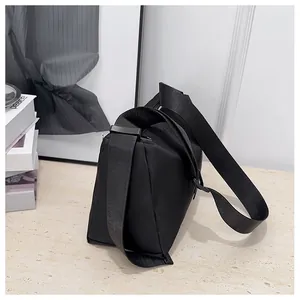 Détail du sac bandoulière noir minimaliste en nylon tissé avec sangle large ajustable