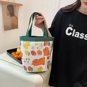 Detail of canvas bucket bag with tiger illustration and green straps held by a model