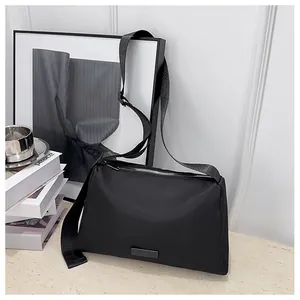 Gros plan sur un sac bandoulière en nylon noir minimaliste avec large sangle et fermeture