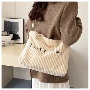 Detail of off-white corduroy tote bag with black TOTE BAG embroidery and striped texture