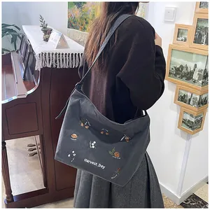 Detail of dark gray corduroy tote bag featuring Harvest Day embroidery and zipper closure