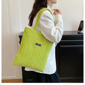 Dettaglio della borsa tote in velluto a coste verde lime con logo Fashion nero e trama a coste