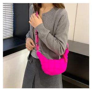 Detail of bright pink quilted crossbody bag with adjustable strap on a female model