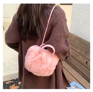 Détail du sac à bandoulière en fausse fourrure rose avec poignée tressée sur modèle