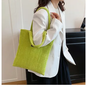 Dettaglio della borsa tote in velluto a coste verde con texture a coste e etichetta nera