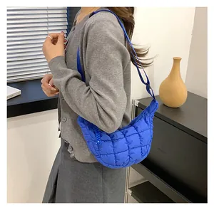 Detail of blue quilted crescent bag with adjustable nylon strap and stitching