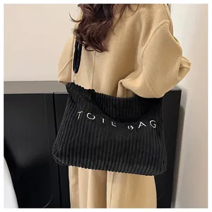 Detail of black corduroy tote bag showing embroidered text and pleated fabric texture