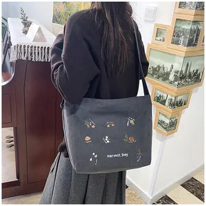 Detail of grey corduroy tote bag showing intricate harvest day embroidery and vertical texture
