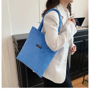 Dettaglio della borsa tote in velluto a coste blu con trama e etichetta Fashion