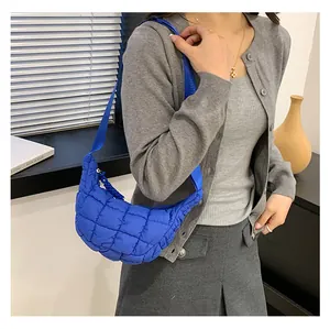 Close-up of bright blue quilted puffer bag with crossbody strap on model