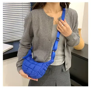 On-body view of electric blue quilted cloud crossbody bag with wide nylon strap