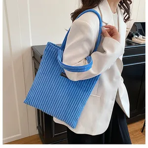 Dettaglio borsa tote in velluto a coste blu con trama a costine su una modella