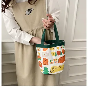Gros plan d'un sac seau en toile avec motifs tigre et anses vertes porté par une personne