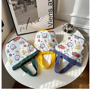 Three colorful canvas bucket bags with cute cartoon rabbit and strawberry prints on a table