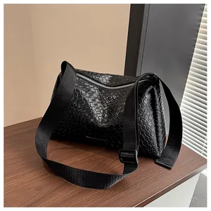Vue détaillée de la texture tressée noire et du zip argenté sur le sac fourre-tout