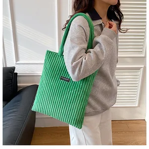 Dettaglio della borsa tote in velluto a coste verde brillante con etichetta alla moda