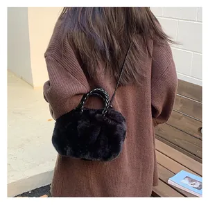 Détail d'un sac à main noir en fausse fourrure avec poignées tressées et fine bandoulière