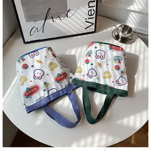 Detail of canvas bucket bags with cute cartoon rabbit and strawberry prints in white