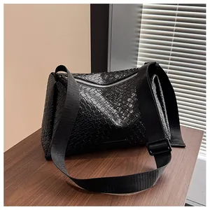 Détail de la texture tressée noire et du zip argenté sur le sac à bandoulière en cuir